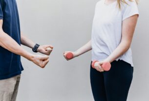 a man and a woman standing next to each other holding dumbs