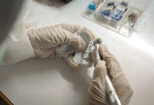 a person with gloves and a pair of scissors